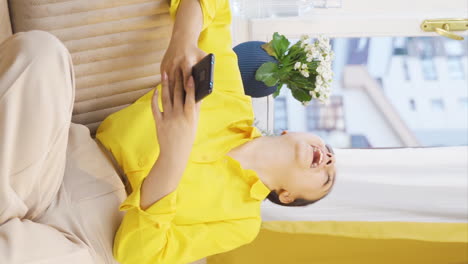 Vertical-video-of-Young-woman-smiling-at-phone-message.